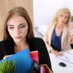 Szef zwalniający pracownika. Przygnębiony zwolniony pracownik biurowy niosący pudełko pełne rzeczy.