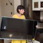 Kobieta z dużą trudnością przynosi nowy duży telewizor LCD do mieszkania
