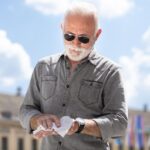 Portret mężczyzny z podniesionymi ramionami stojącego przed niebem