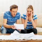 Napięta para patrząca na dokument siedząc w domu