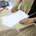 Środkowa sekcja kobiety biznesmenki składającej papier przy biurku w biurze