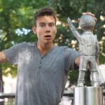 Portret wstrząśniętego młodego mężczyzny stojącego przy posągu