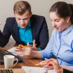 Pracowników biurowych siedzi przy biurku rozmawiając