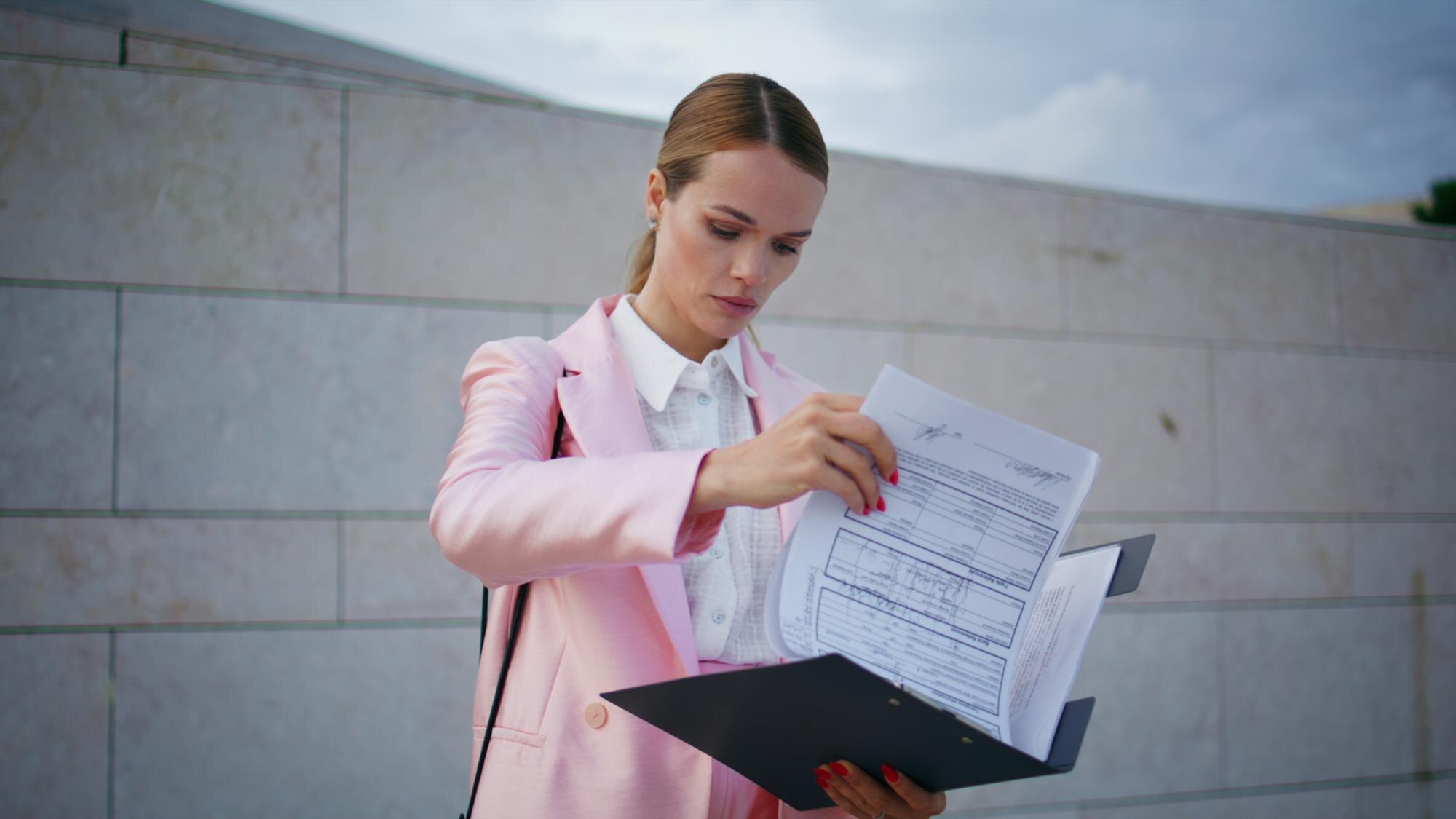 Elegantny dyrektor czyta raport na ulicy, bizneswoman sprawdza dokumenty.