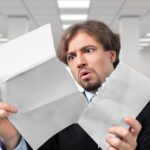 Mężczyzna otwiera list z szokującym wyrazem twarzy