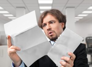 Mężczyzna otwiera list z szokującym wyrazem twarzy