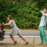 Mężczyzna i kobieta pchają zepsuty samochód na drodze, awaria