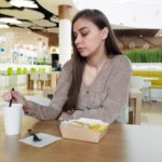 Młoda kobieta je fast food w restauracji