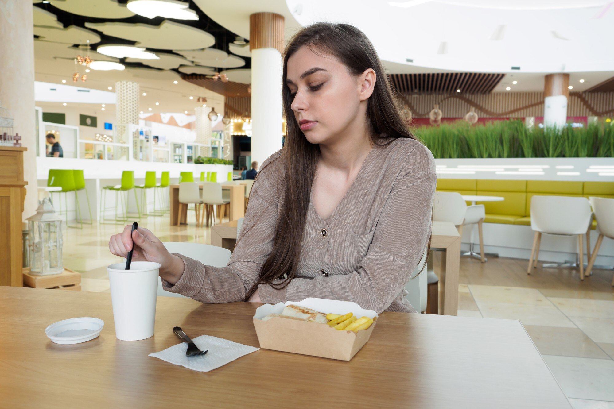 Młoda kobieta je fast food w restauracji