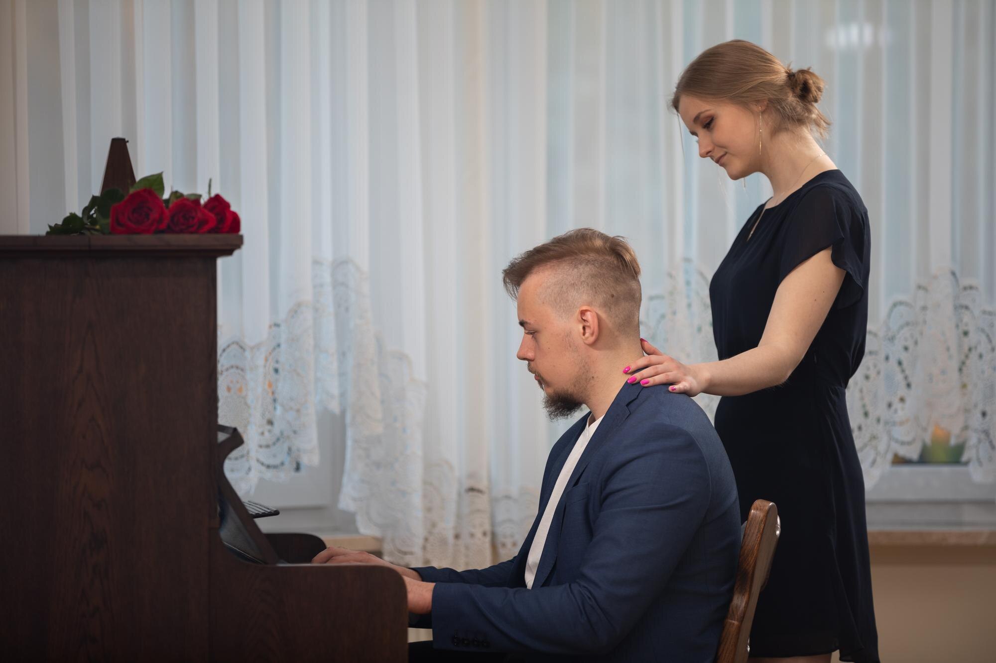 Muzyk gra na pianinie, a jego kobieta przechodzi obok.