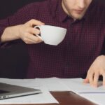 Atrakcyjna praca studencka z papierem i laptopem oraz picie kawy na ciemnym tle b