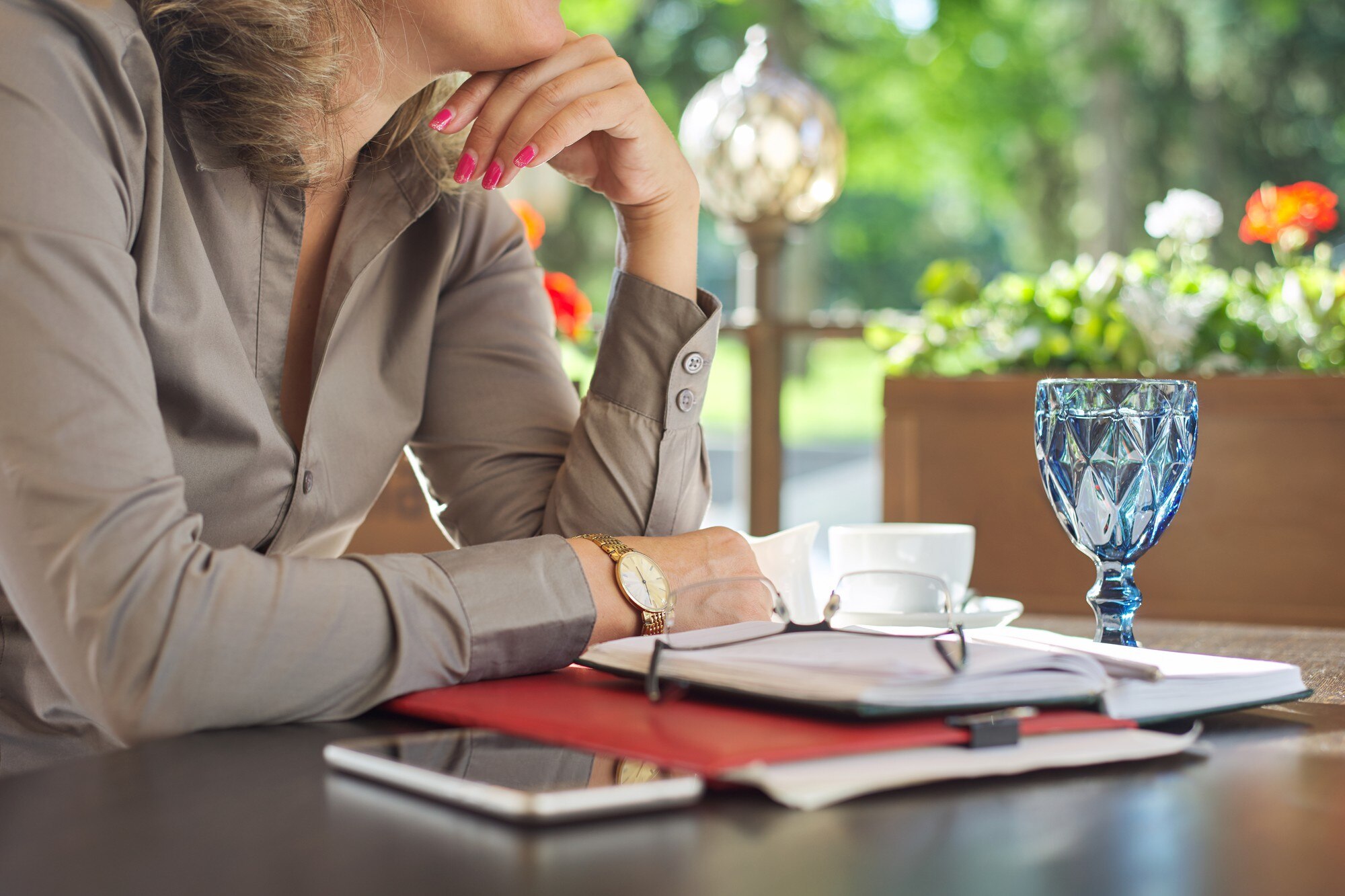 Przerwa na kawę, stół w restauracji na świeżym powietrzu, dokumenty biznesowe, notebook, smartfon, okulary, filiżanka kawy. Odpoczywająca kobieta biznesu