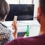 Widok z tyłu przyjaciół oglądających telewizję i trzyma pilota w ręku.