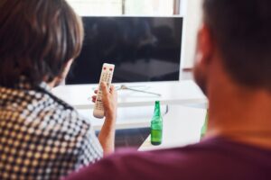 Widok z tyłu przyjaciół oglądających telewizję i trzyma pilota w ręku.