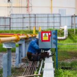 Mężczyzna naprawia rozdzielnicę wysokiego napięcia za pomocą automatycznych wyłączników.