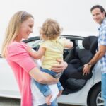 Rodzice niosący dziecko i jej fotelik samochodowy