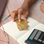ręka osoby trzymającej kartę kredytową na stole
