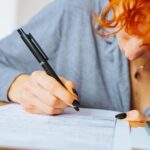 Portret atrakcyjnej nastolatki wypełniającej formularz