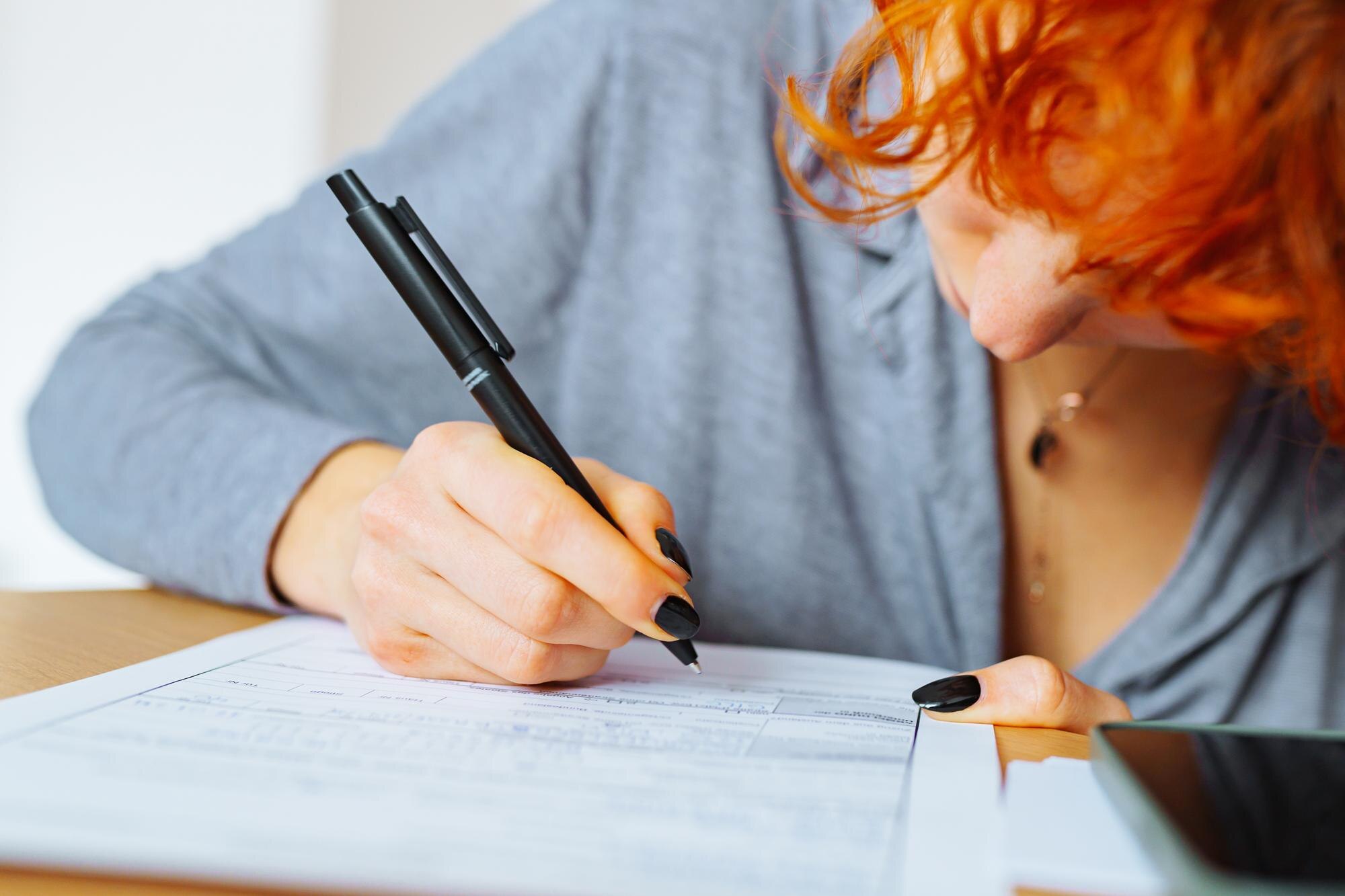 Portret atrakcyjnej nastolatki wypełniającej formularz