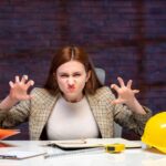 widok z przodu zła kobieta inżynier siedząca za swoim miejscem pracy program budowniczy pracy biznes plan korporacyjny wykonawca sukces majątkowy