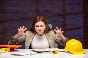 widok z przodu zła kobieta inżynier siedząca za swoim miejscem pracy program budowniczy pracy biznes plan korporacyjny wykonawca sukces majątkowy