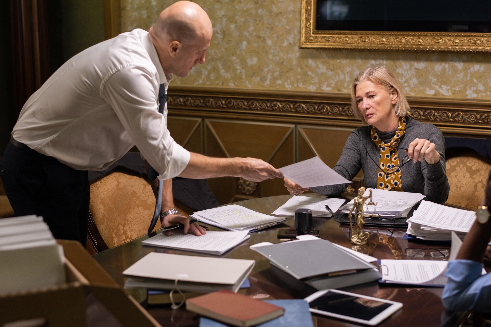 Łysy biznesmen przekazuje papier swojej dojrzałej koleżance