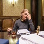 Blond dojrzała prawniczka dotyka głowy podczas pracy w godzinach nadliczbowych