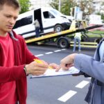 Mężczyzna i kobieta wypełniają dokumenty po wypadku samochodowym