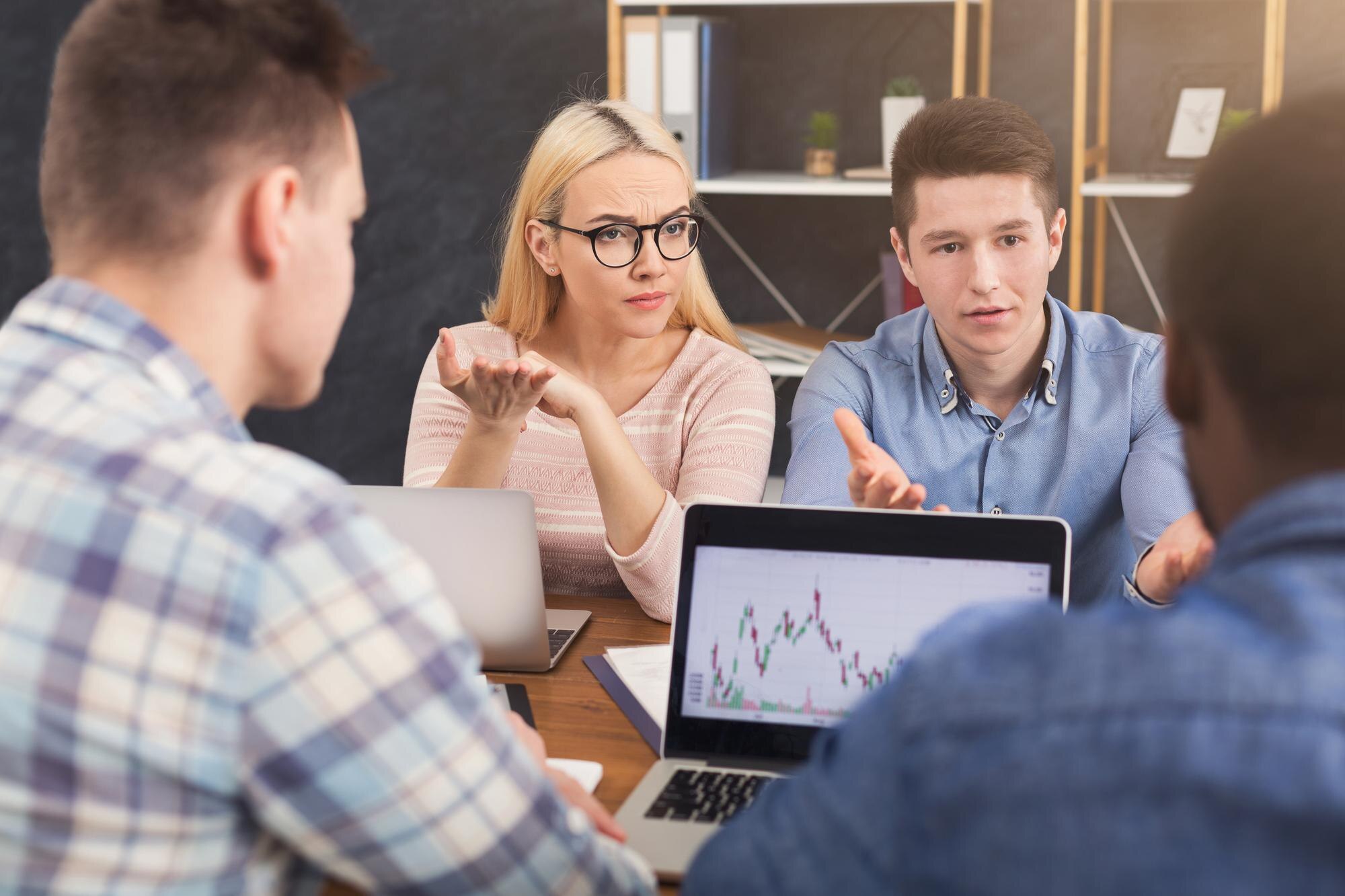 Zespół biznesowy opowiada o wynikach swojej pracy. Grupa zmartwionych biznesmenów studiujących wykres na laptopie, omawiających nową strategię marketingową, siedzących w biurze, kopiujących przestrzeń