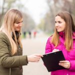 Dwie kobiety rozmawiają z tabliczką na ścieżce w parku