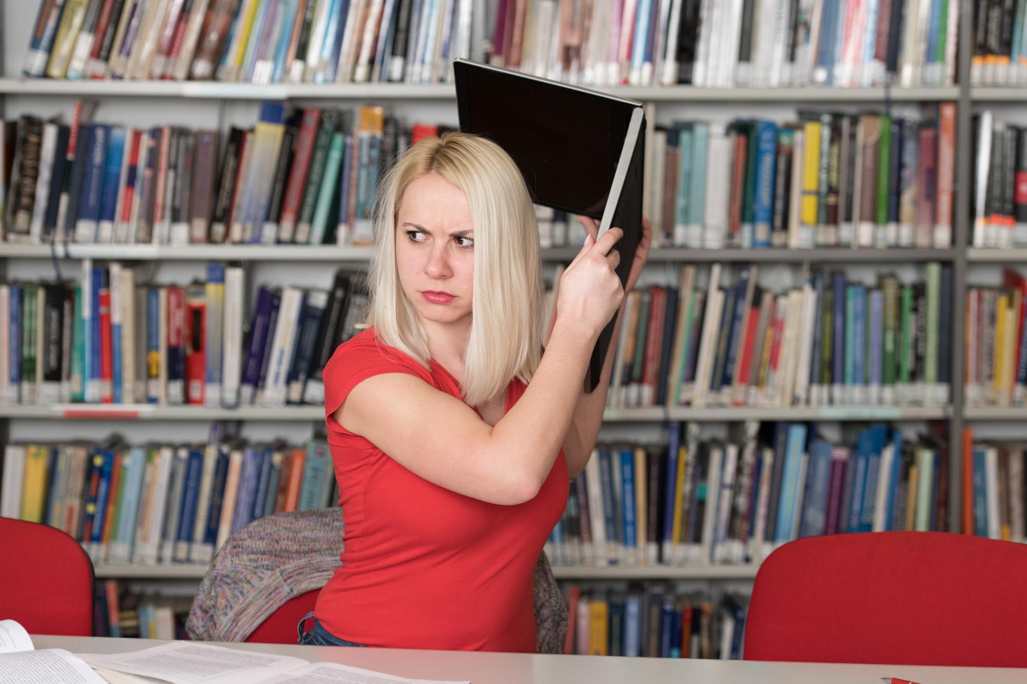 Przystojna studentka rzucająca laptopem i chce go zniszczyć