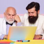 Współpraca biznesowa Starzy biznesmeni dzielą się doświadczeniami z młodym współpracownikiem w biurze Biznesmen pracujący z laptopem w miejscu pracy