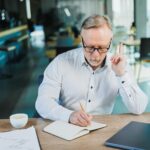 Dojrzały biznesmen pracuje siedząc w biurze kierownik w średnim wieku pracuje w biurze za pomocą laptopa emocjonalny biznesmen