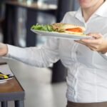 Kelnerka niesie do klienta talerz z jedzeniem