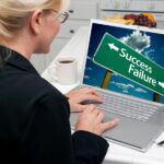 Kobieta w kuchni używająca laptopa z znakiem drogowym sukcesu i porażki na ekranie