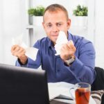Młody biznesmen pracujący w biurze bardzo zaniepokojony paniką zmięty papier