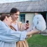 Mama i jej nastoletni syn śmieją się fotografując dekoracyjnego królika na smartfonie