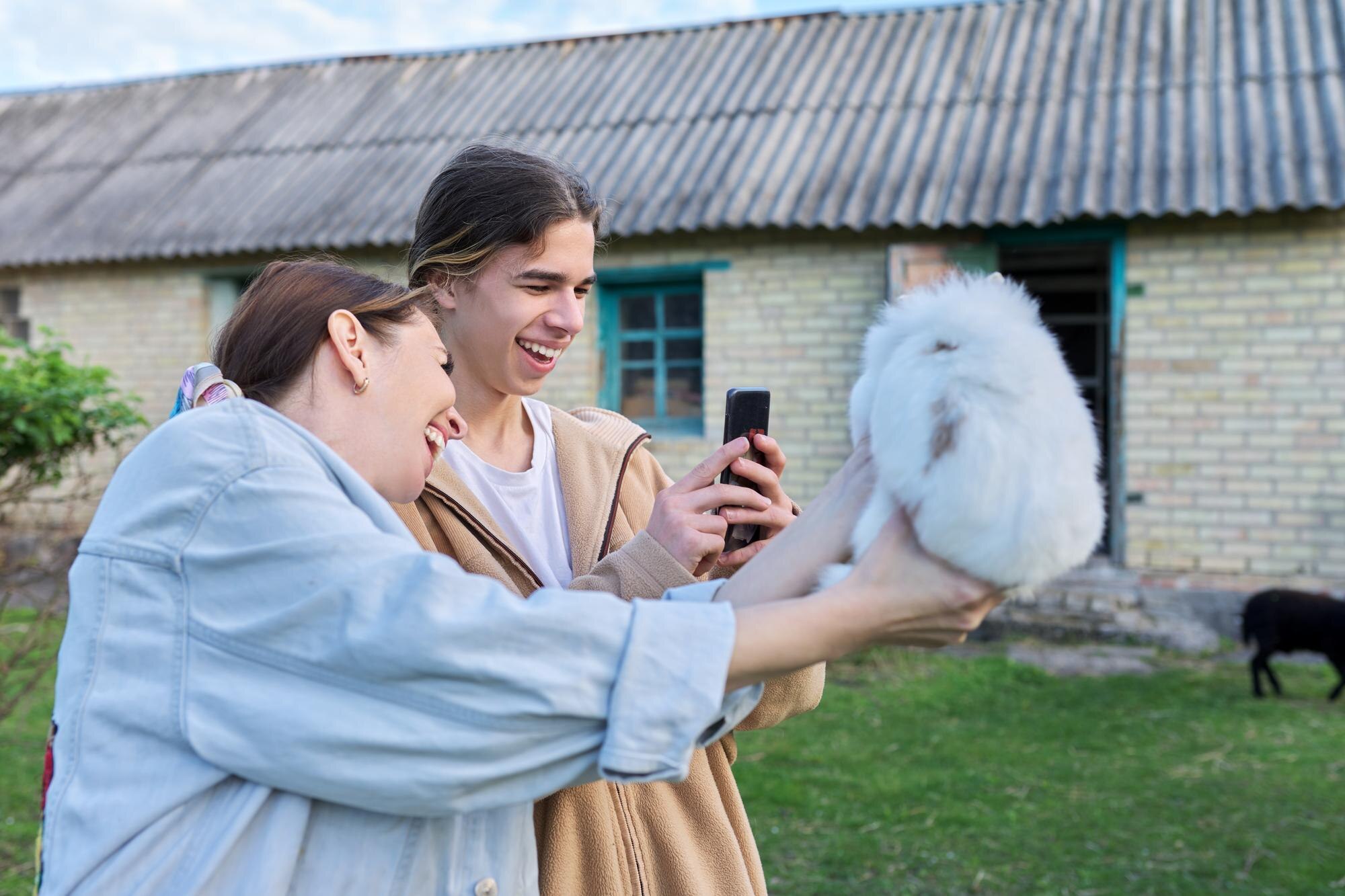 Mama i jej nastoletni syn śmieją się fotografując dekoracyjnego królika na smartfonie