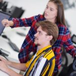 para biznesowa pracująca razem nad projektem przy użyciu tabletu i komputera stacjonarnego w nowoczesnym biurze startowym na otwartym planie