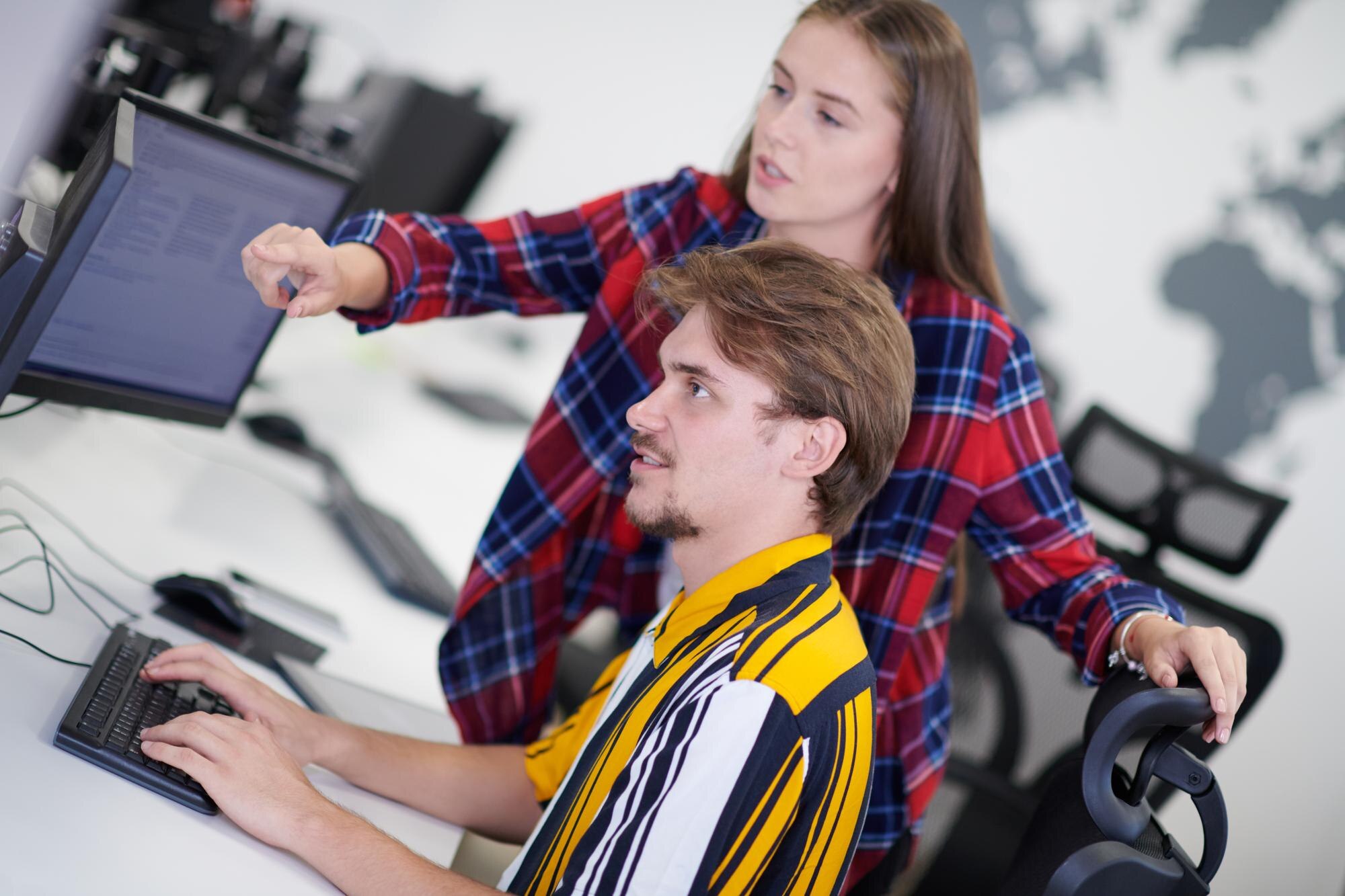 para biznesowa pracująca razem nad projektem przy użyciu tabletu i komputera stacjonarnego w nowoczesnym biurze startowym na otwartym planie