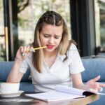 Młoda dziewczyna trzymająca długopis i patrząca na swoje notatki w restauracji