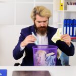 Brodaty biznesmen z koszem na śmieci pracownik biurowy z koszem na śmieci dyrektorem ds. recyklingu papieru biznesowego