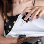 Ręce kobiety pracujące w stosach papierowych plików