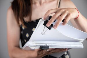 Ręce kobiety pracujące w stosach papierowych plików