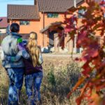Z tyłu młoda para patrząca na swój nowy dom
