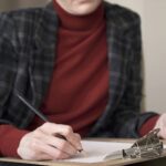 Kobiece ręce kierownika na krześle robienia notatek w papierze trzymającym ołówek