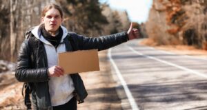Młody mężczyzna podróżuje autostopem po kraju Mężczyzna próbuje złapać przejeżdżający samochód na podróż Mężczyzna z plecakiem pojechał autostopem na południe