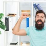 Szczęśliwy człowiek wykonujący zwycięski gest słuchający słuchawek w muzyce biurowej