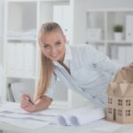 Portret kobiety architekta z projektami przy biurku w biurze