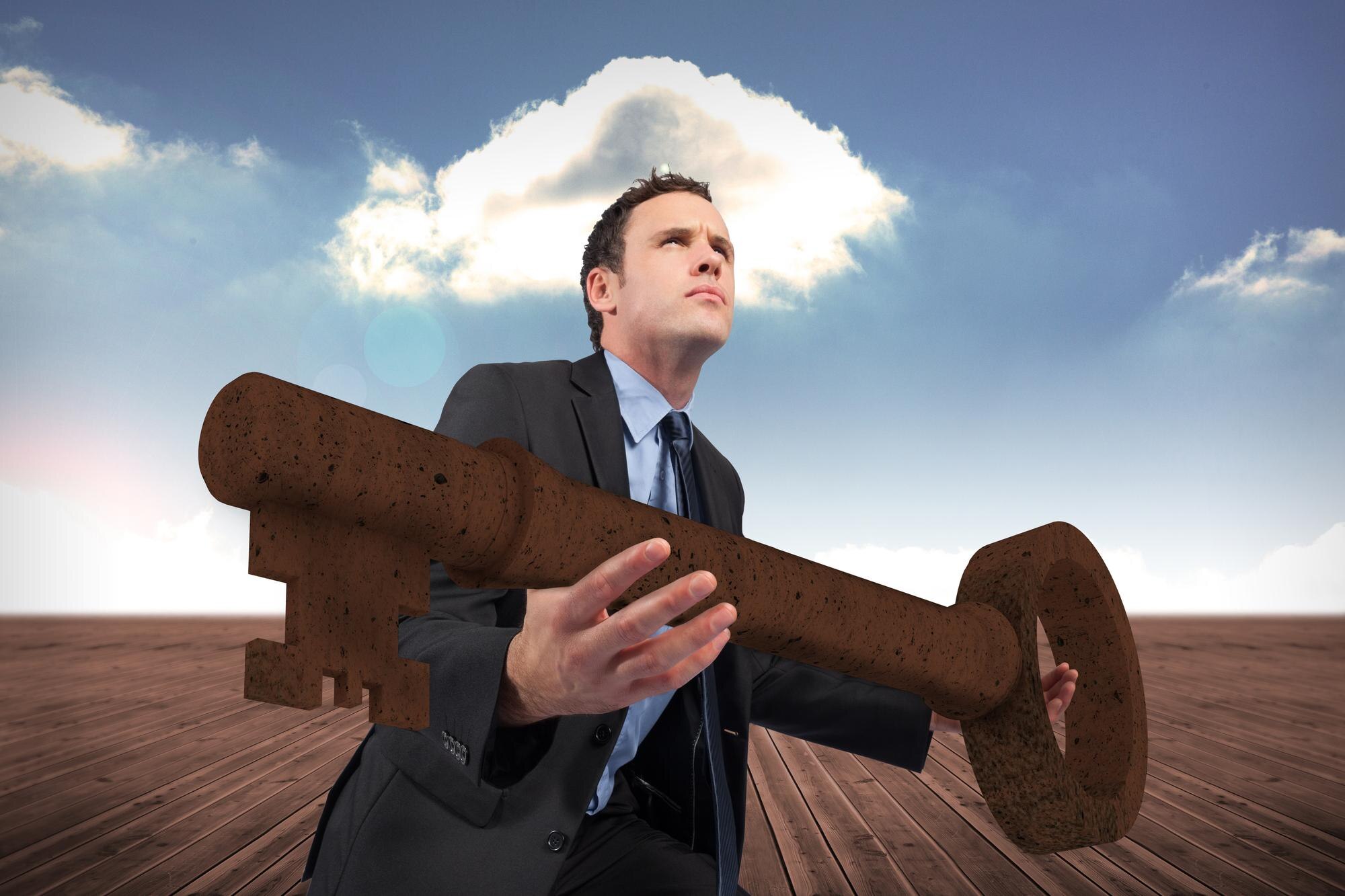 Biznesmen niosący duży klucz z bronią na tle pochmurnego nieba